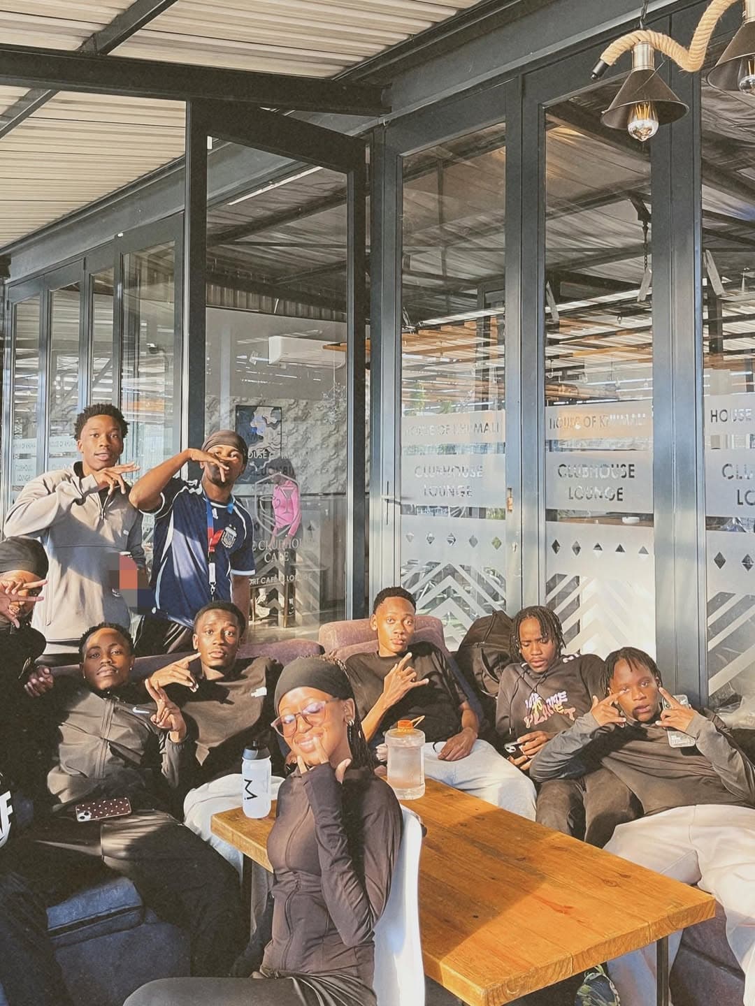 Group portrait in front of the House of Khumali clubhouse signage