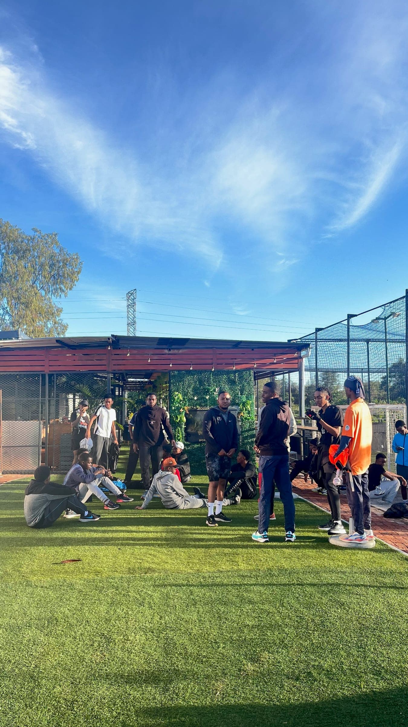 Members sitting out on the grass by the clubhouse under a bright blue sky