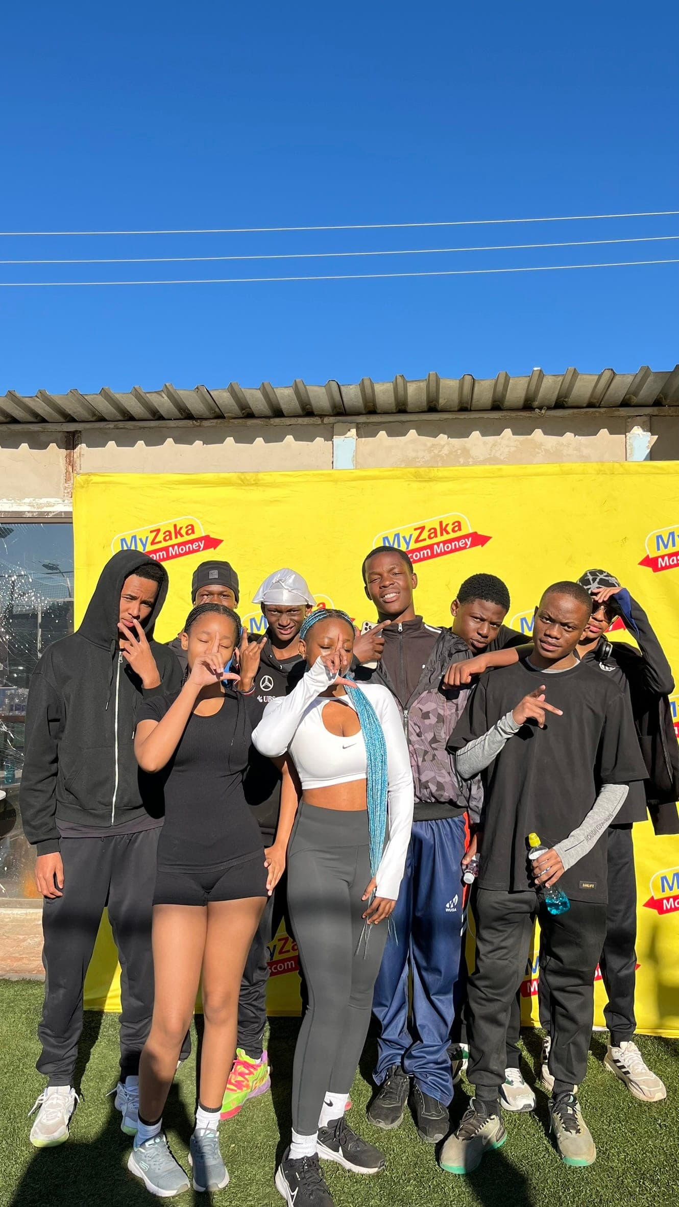 Group of eight members posing together against a bright yellow wall after a run
